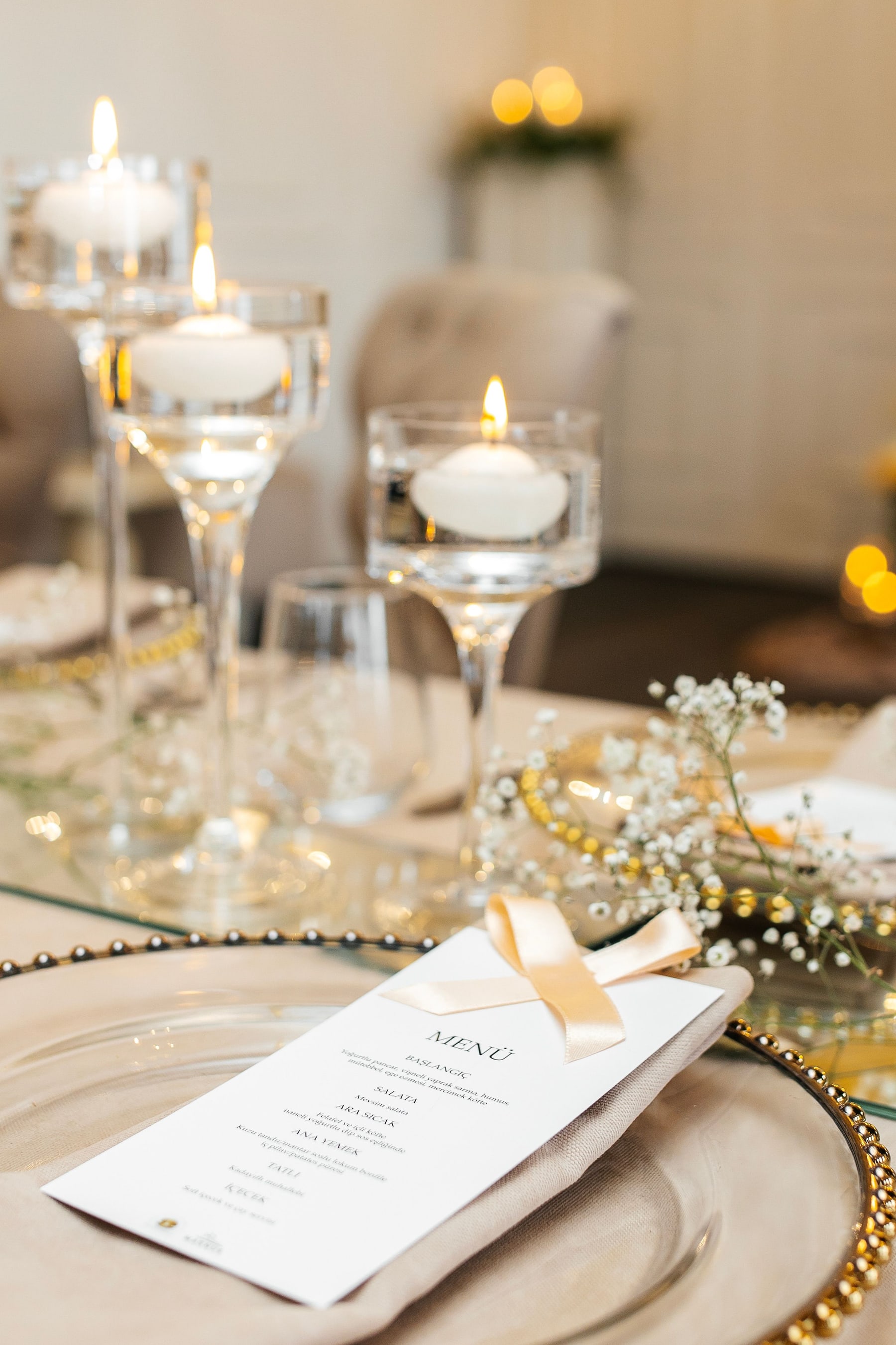 Lit floating candles in clear glass vessels on an elegant wedding reception table