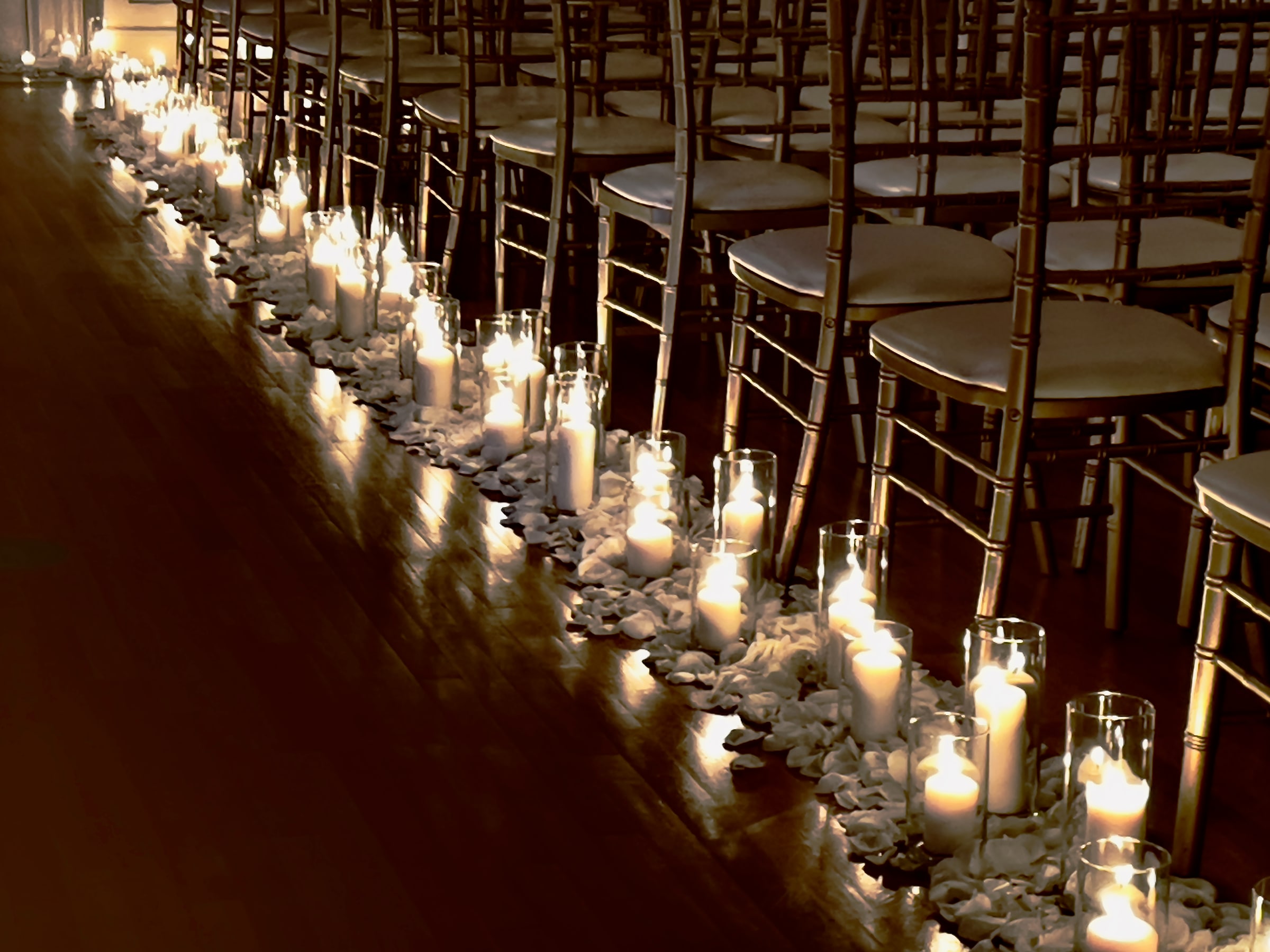 Candlelit glass cylinders lining a ceremony aisle
