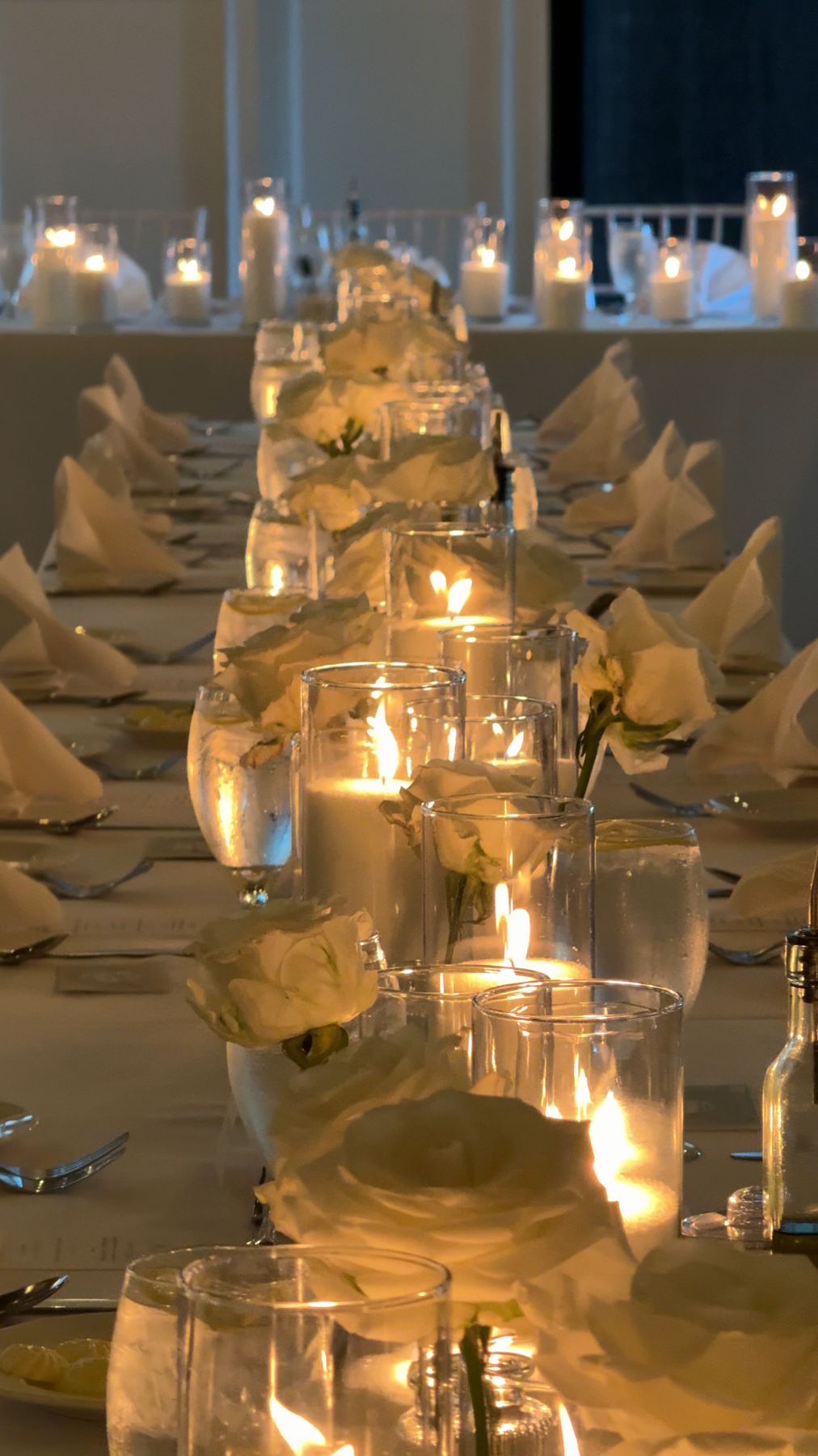Layered candlelight and florals along a long reception table