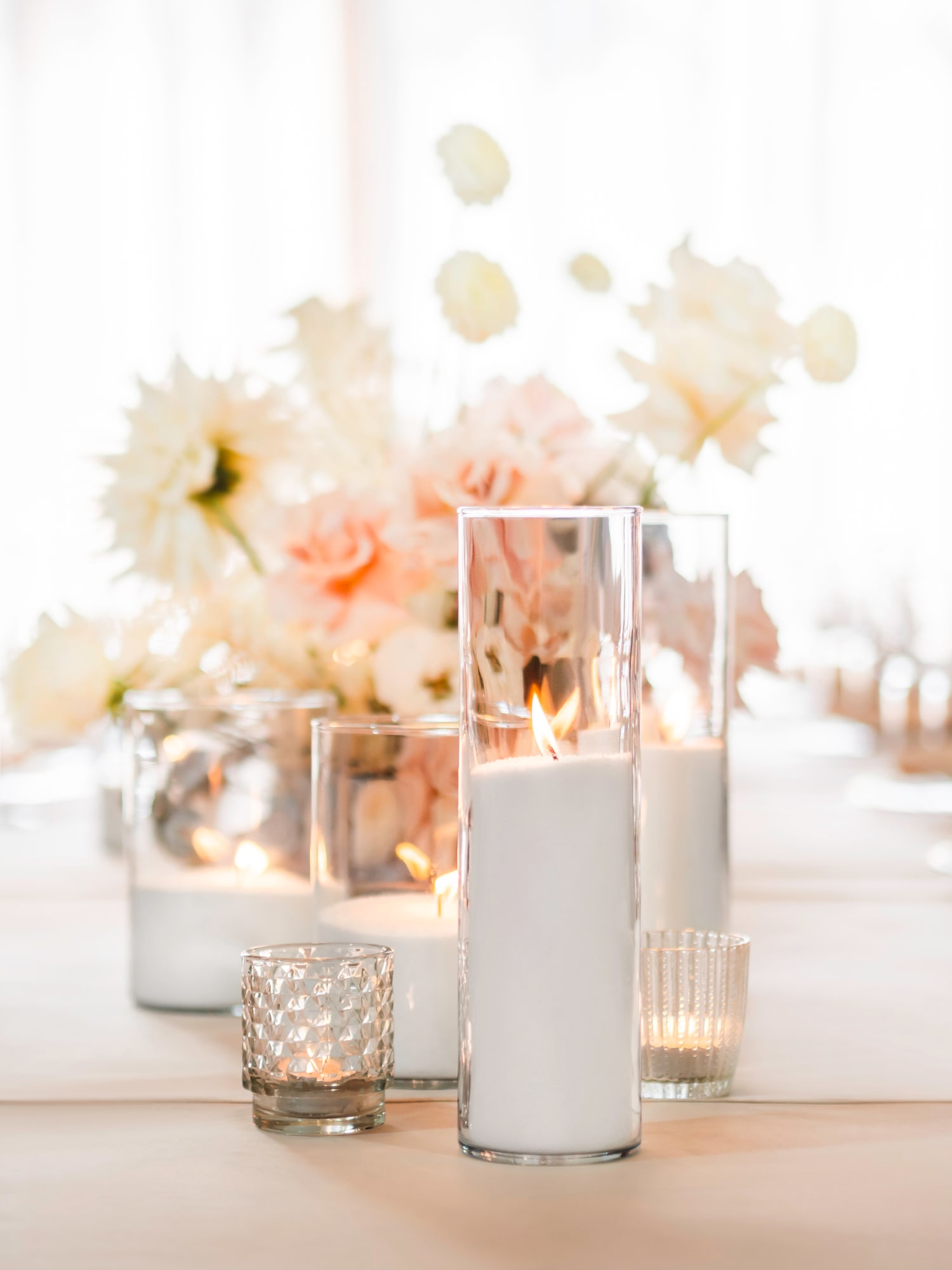 White pillar candles with sand wax in layered glass cylinders