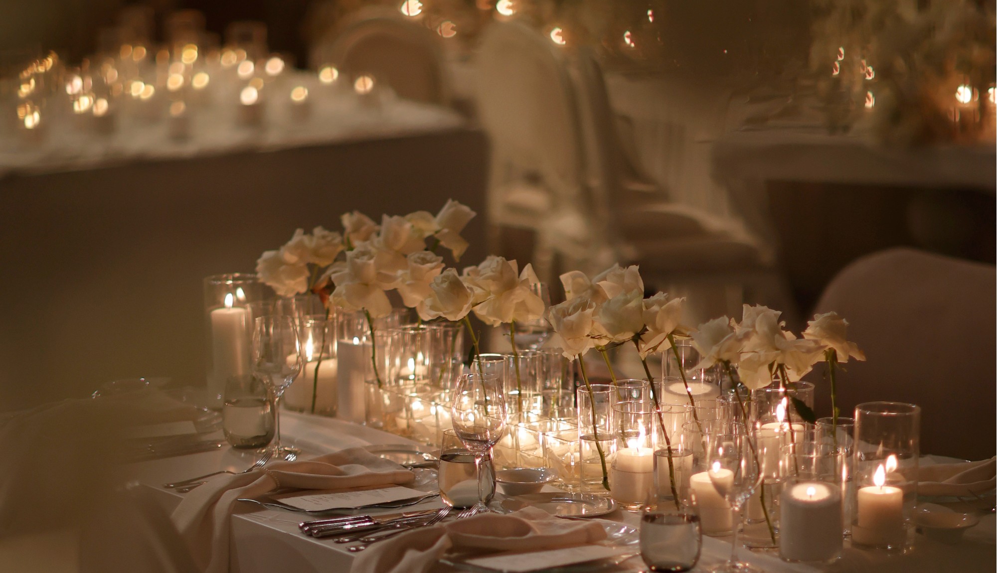 Long reception table layered with Candlelit glass cylinders and candlelight