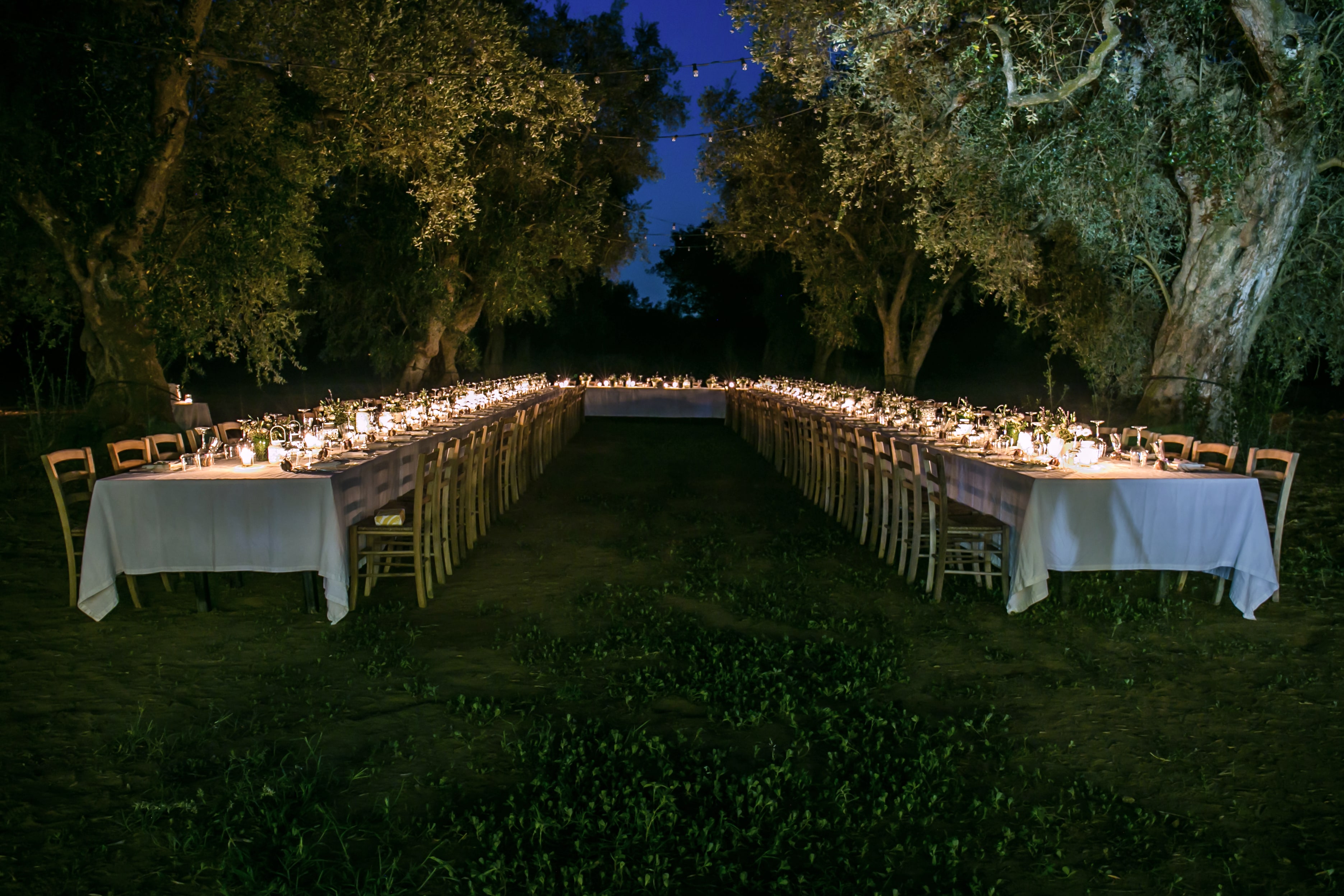 Outdoor reception tables illuminated by candlelight at dusk
