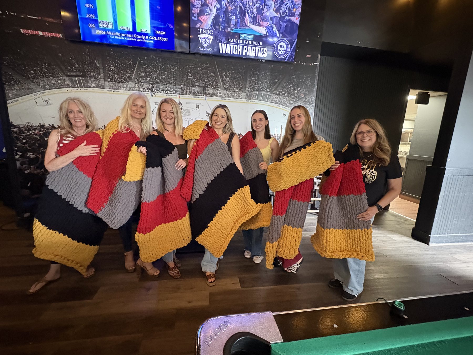Workshop guests holding colorful chunky knit blankets
