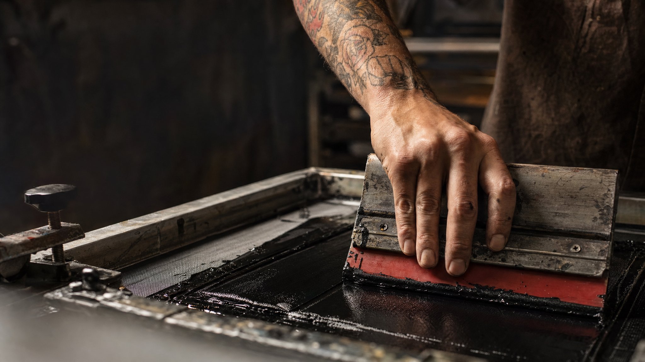 Screen printer pulling ink across a mesh screen