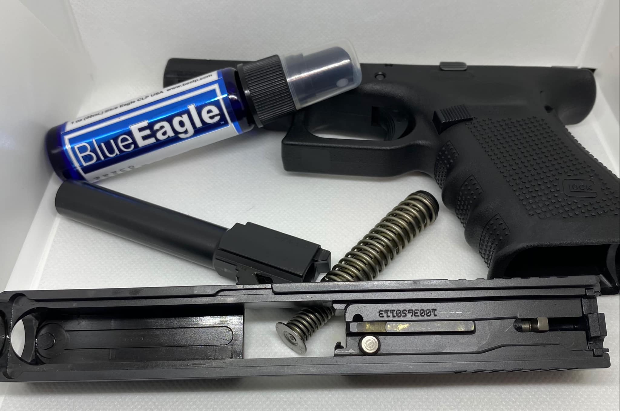 BlueEagle CLP product displayed beside a firearm on a workbench