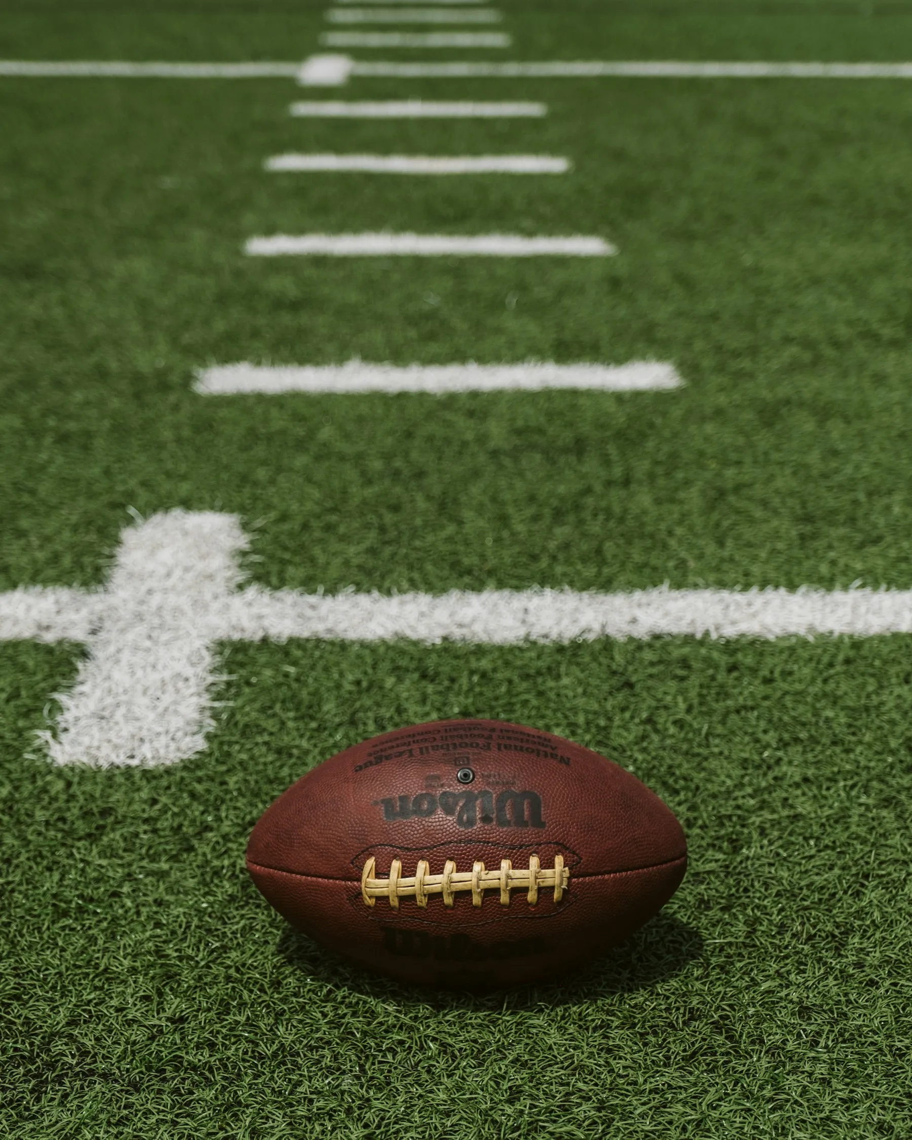 American football resting on a green field
