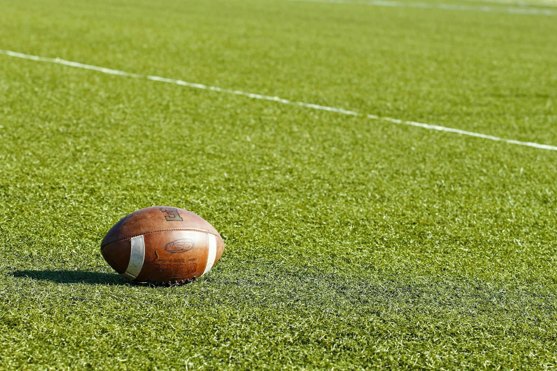 American football standing on a green field