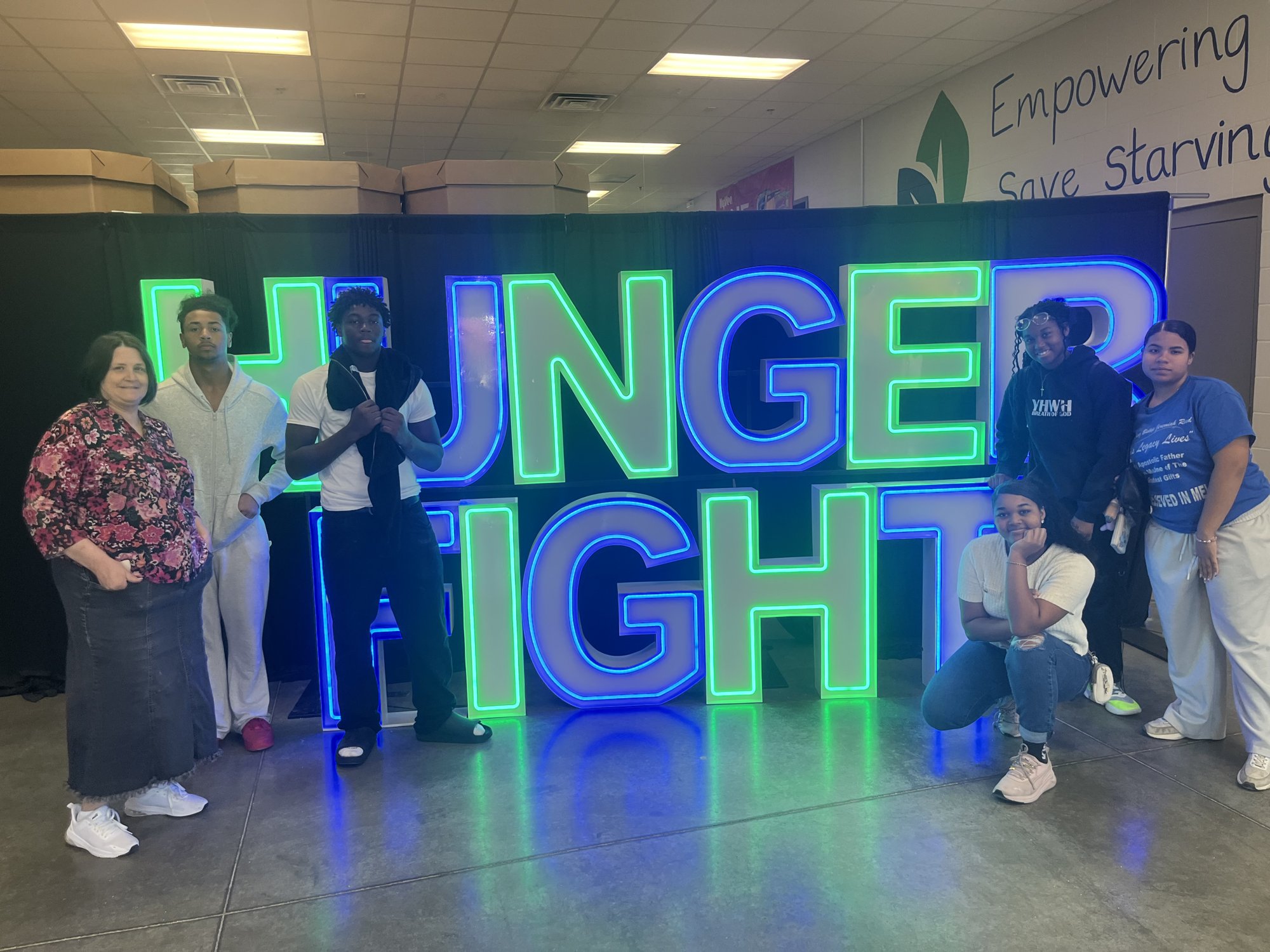 JWRCA students and Administrator Tara Ross beside the Hunger Fight sign