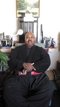 Grandmaster Ralph Anthony Kemmerlin, Sr., seated in his office wearing his martial arts uniform