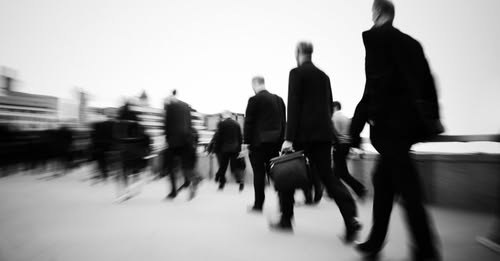 Blurred black-and-white view of professionals walking through a public space