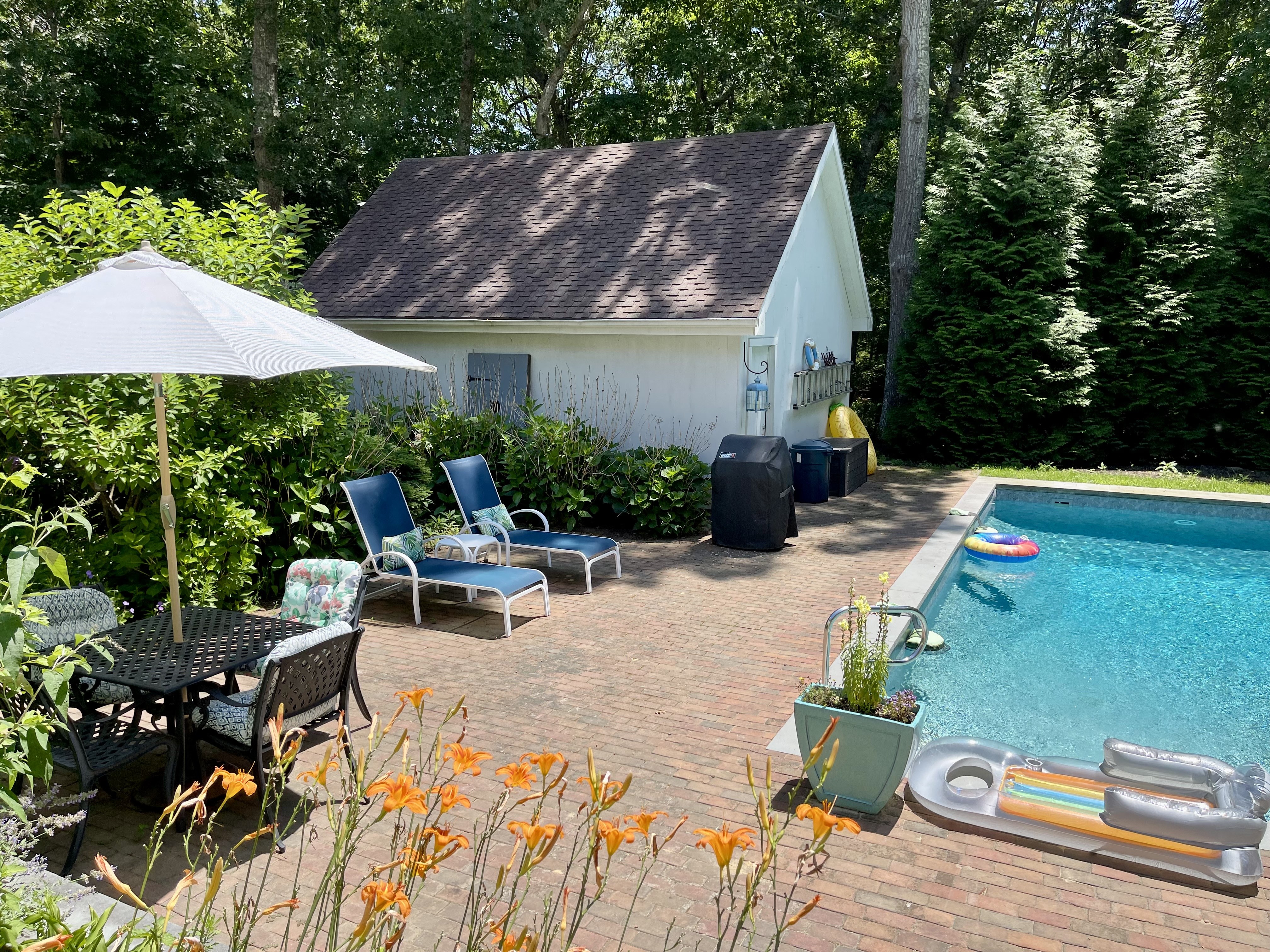 Private pool patio with loungers, dining table, and flowering garden
