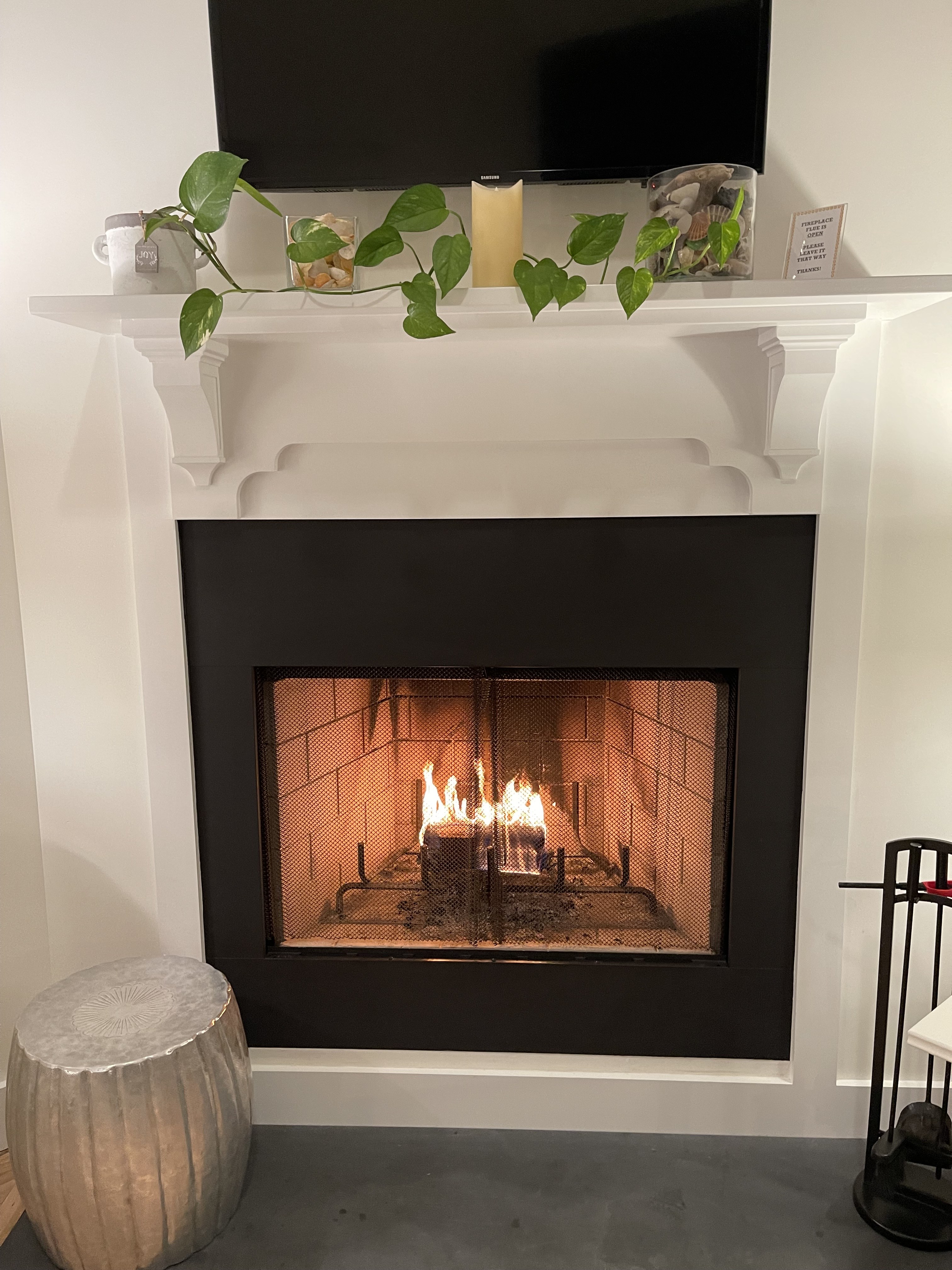 Lit fireplace with beach glass and greenery in the Beachglass Barn suite