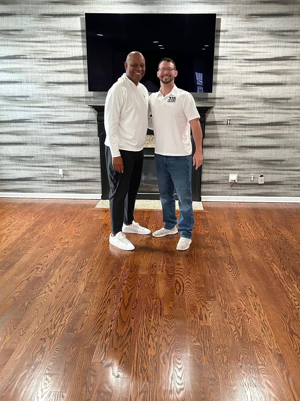 A 315 Hardwoods team member standing on a completed hardwood floor