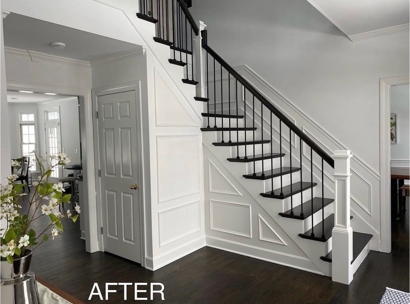 Completed staircase remodel with dark treads, black balusters, and white newel posts