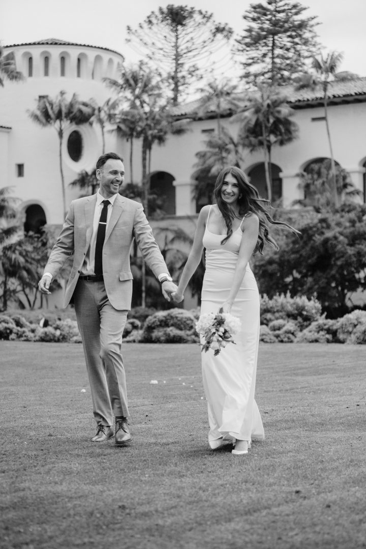 Newlyweds holding hands on the lawn at the Santa Barbara Courthouse