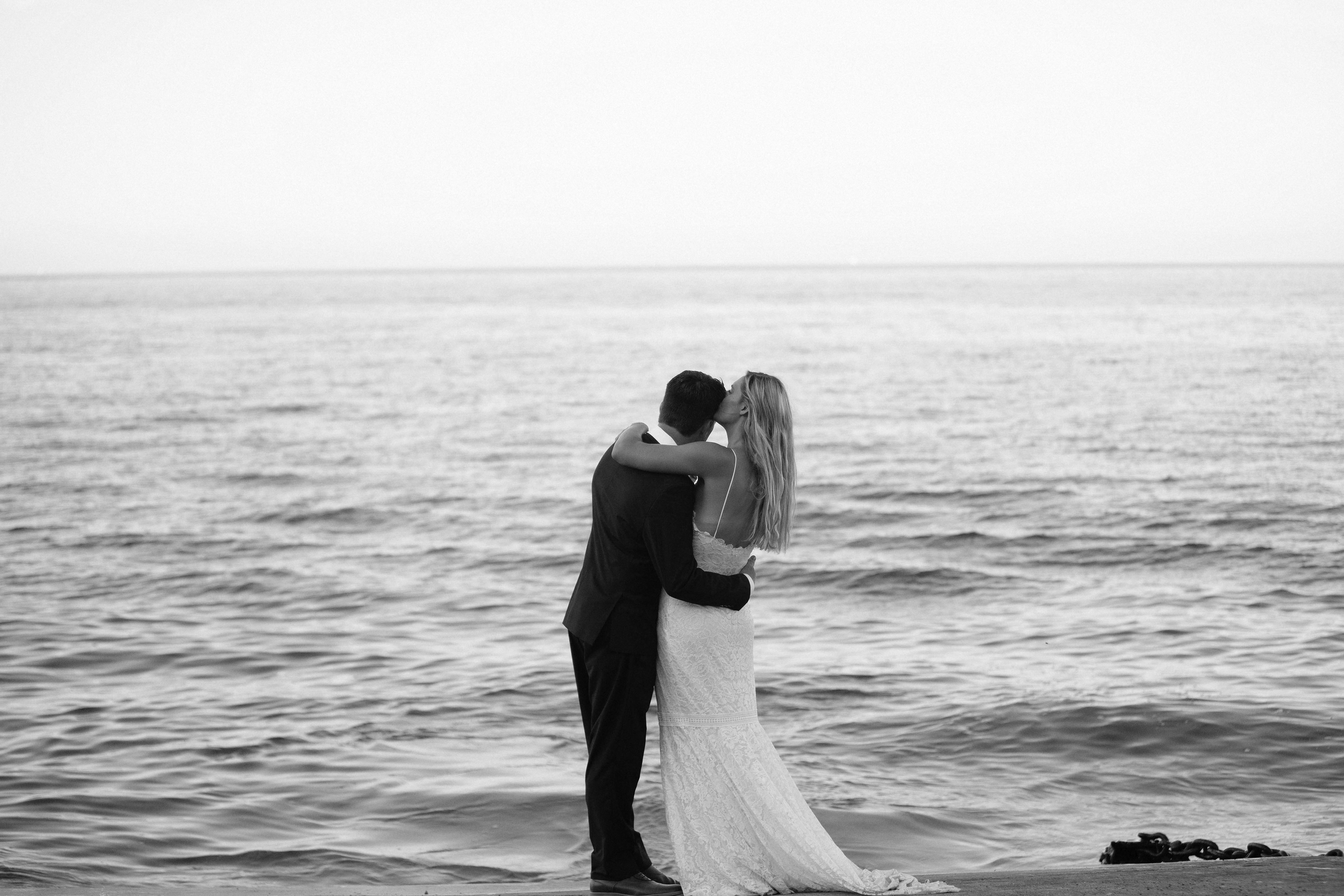 Newlyweds embracing beside the ocean