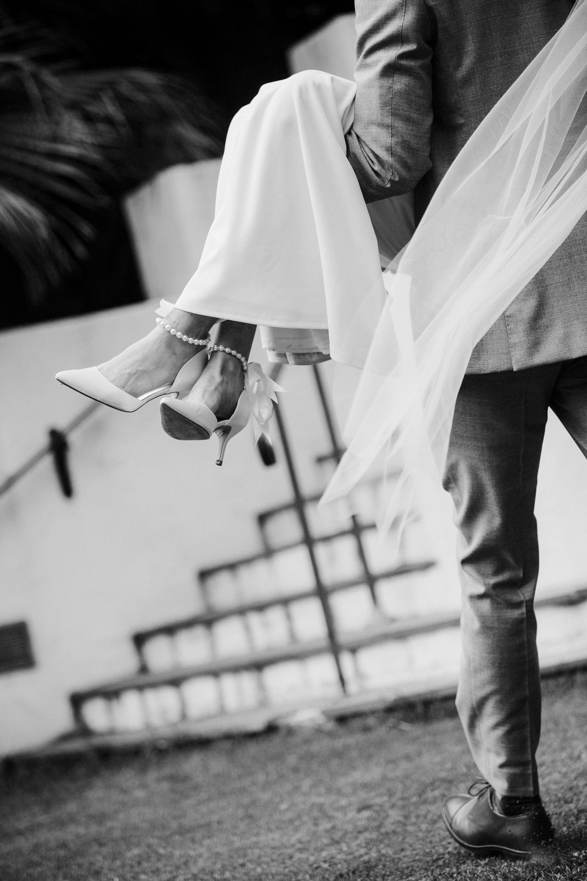 Newlywed couple walking together, with the bride lifted off the ground