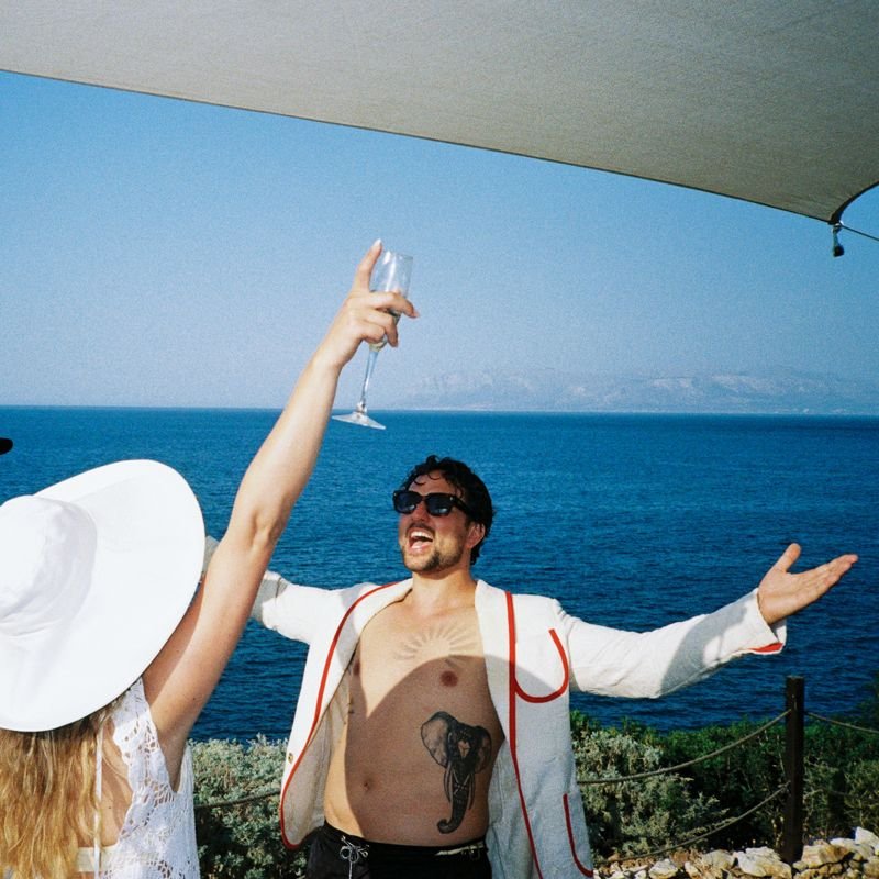 Couple raising champagne over the Sicilian coast