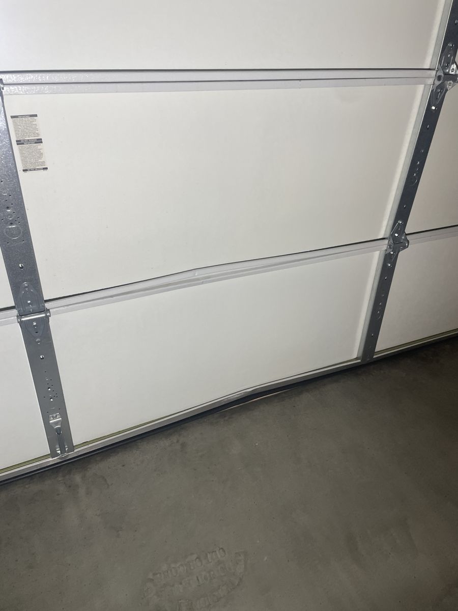 Dented bottom garage door panel before repair
