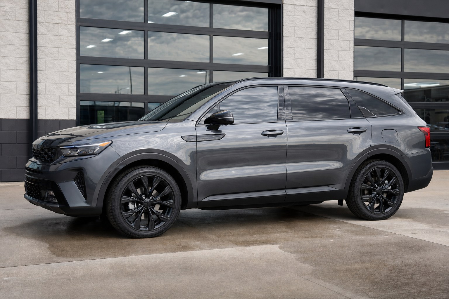 Finished gray SUV with clean, dark automotive window tint outside a professional tint shop