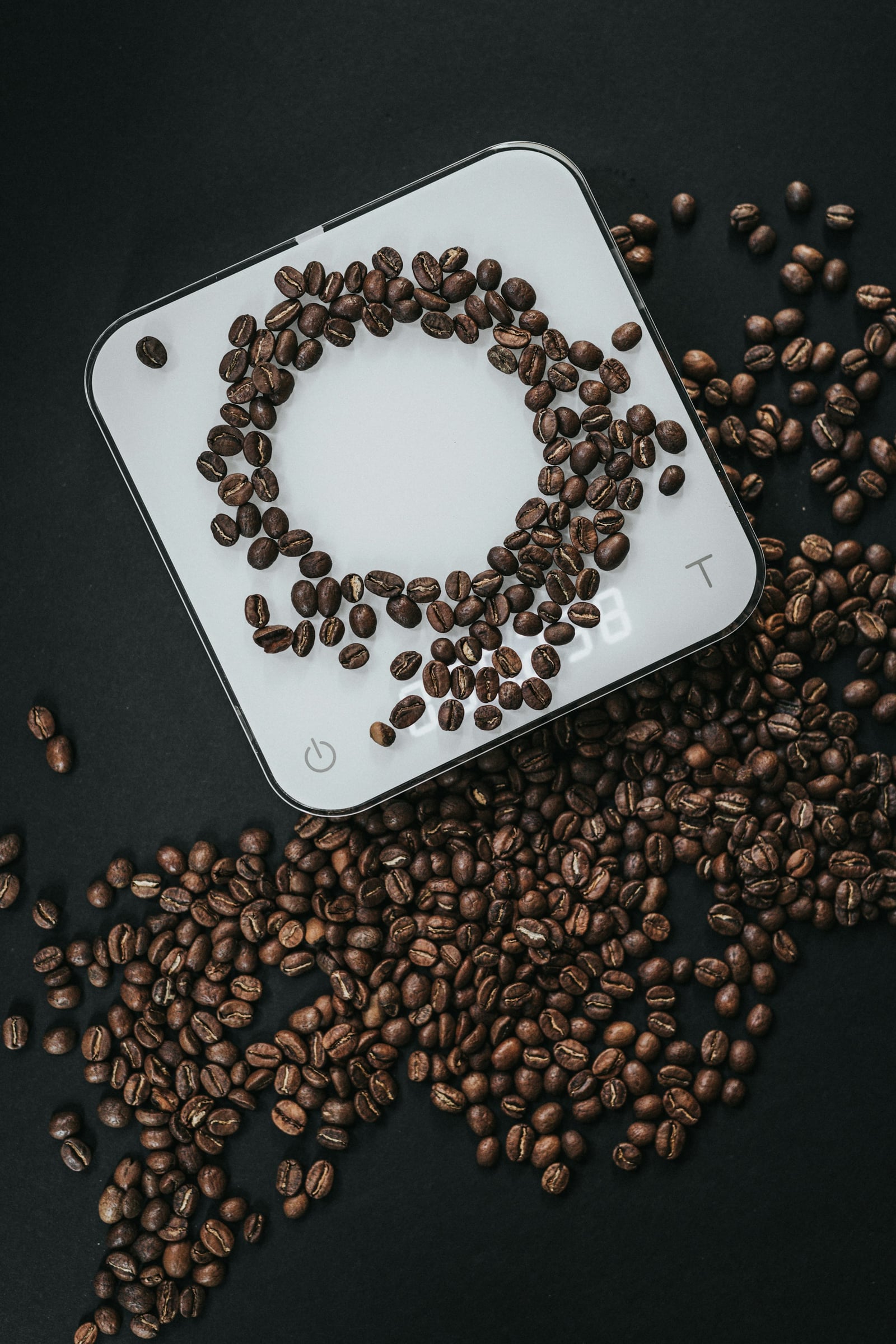 Roasted coffee beans arranged on a white digital kitchen scale