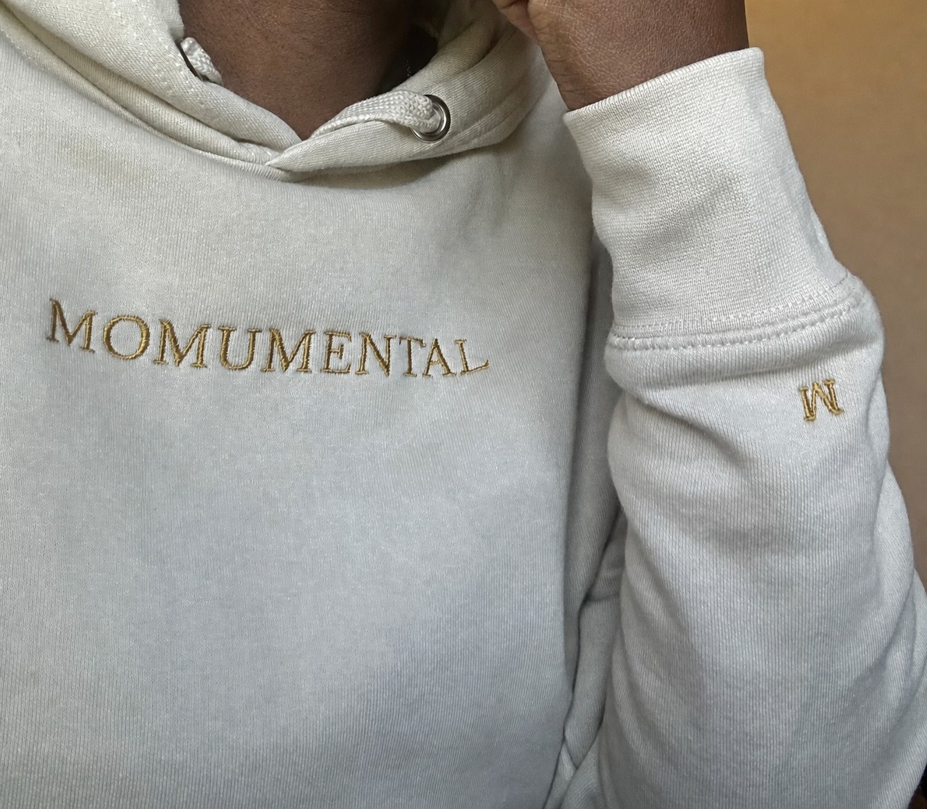 Woman wearing a neutral Momumental hoodie in a quiet home setting