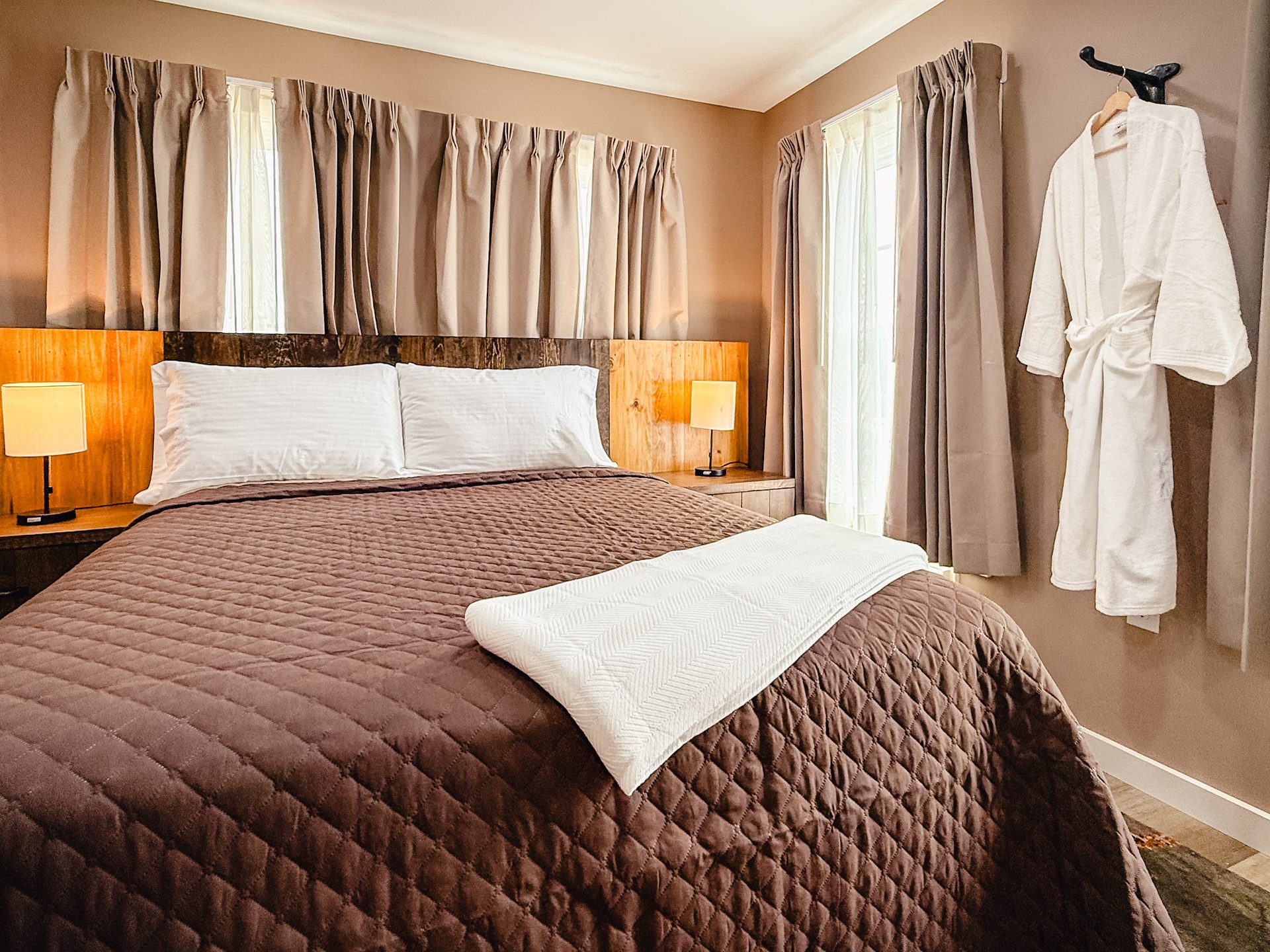 A comfortable guest room at Stable Craft Brewing with a quilted bed and white bathrobes
