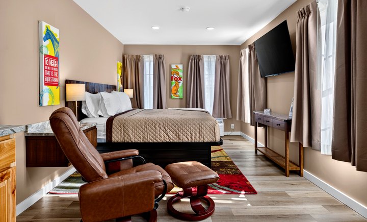 Meadow Summit · Loft 202: Room overview with bed and leather lounge chair