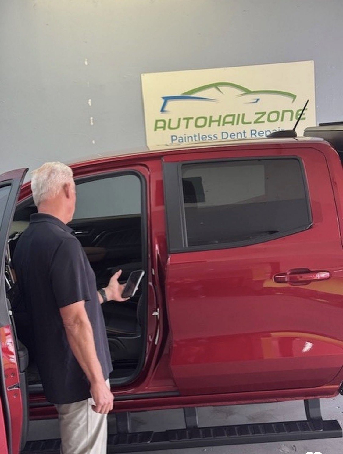 Auto Hail Zone technician inspecting a red vehicle in the shop