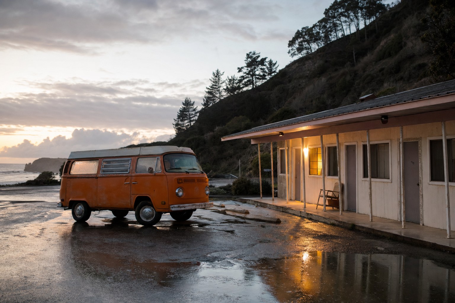 Orange vintage camper outside a weathered roadside motel after rain at the coast