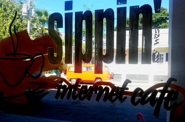 An orange Volkswagen camper seen through the window of Sippin’ internet café in Key West