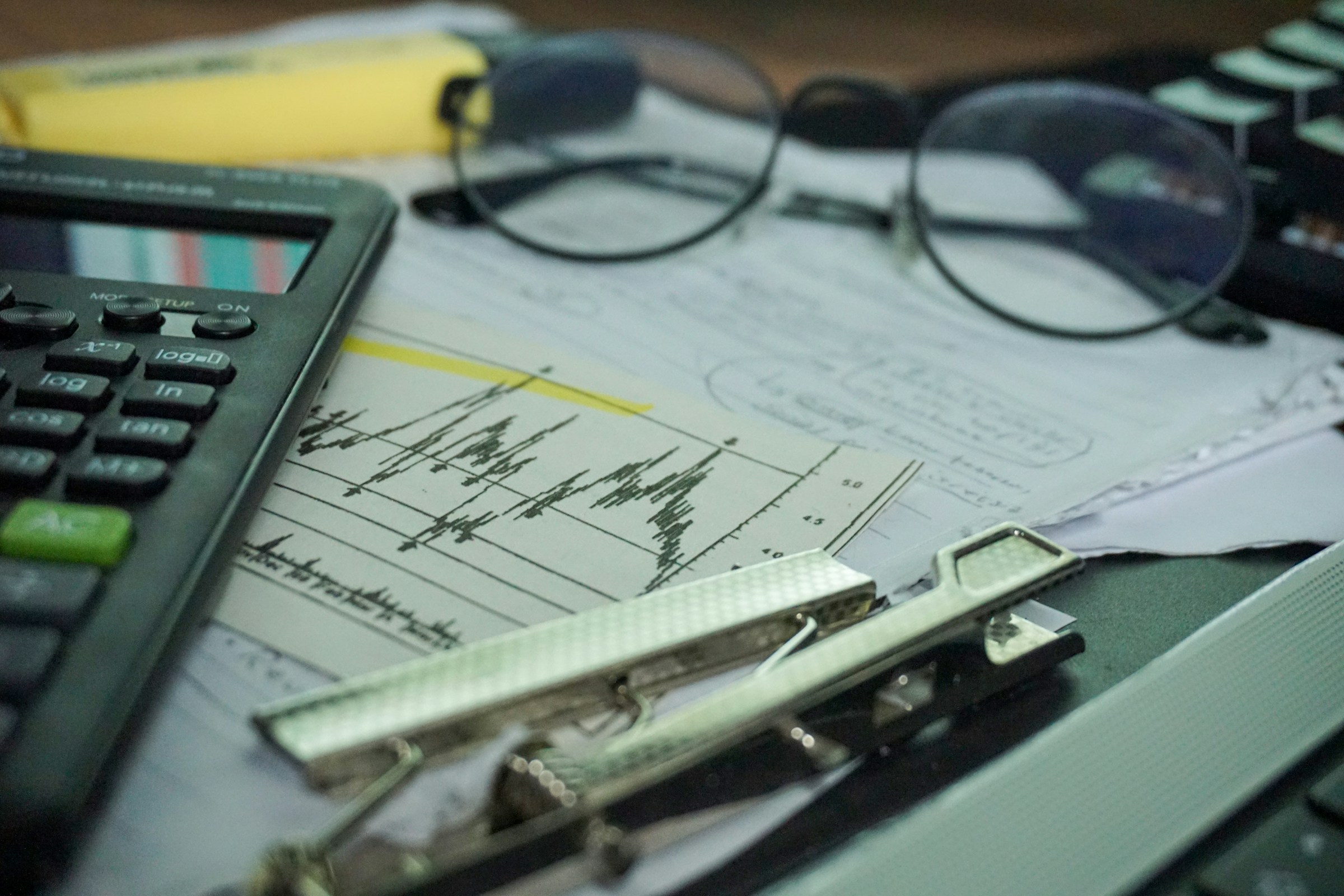 Calculator, paperwork, and eyeglasses organised on a desk for claim preparation