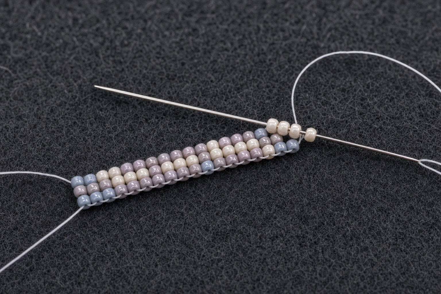 A beading needle passing through the first rows of seed bead weaving