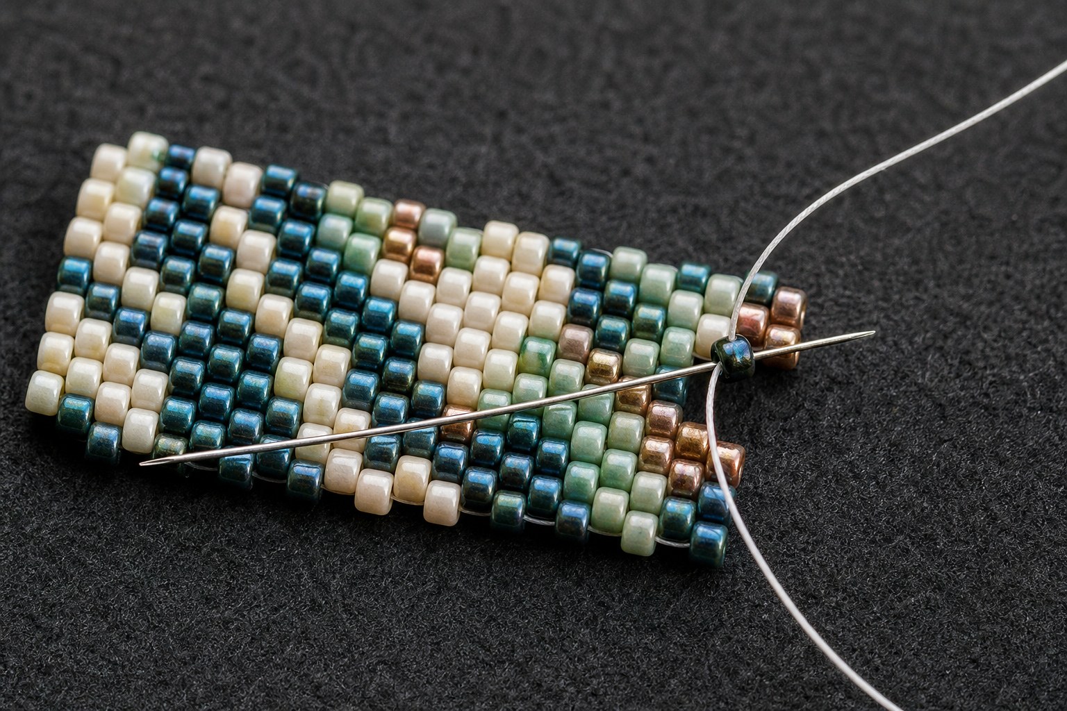 Beading needle passing through the raised edge of peyote stitch