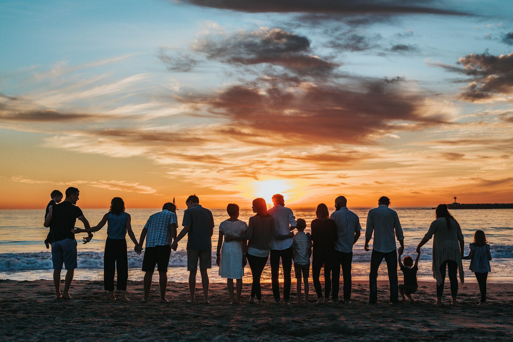 Extended family standing together on a beach at sunset
