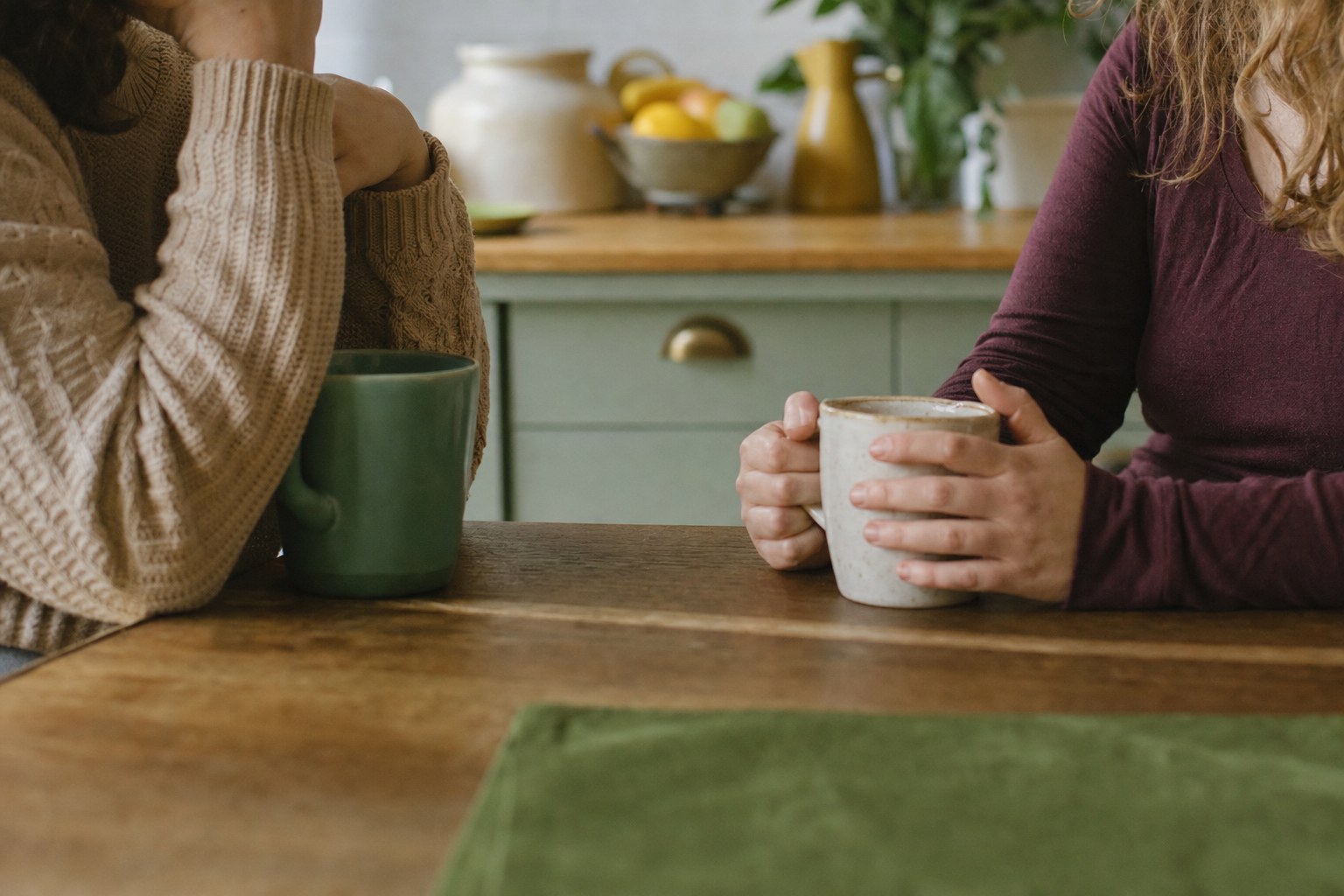 Two people having a quiet conversation at a kitchen table