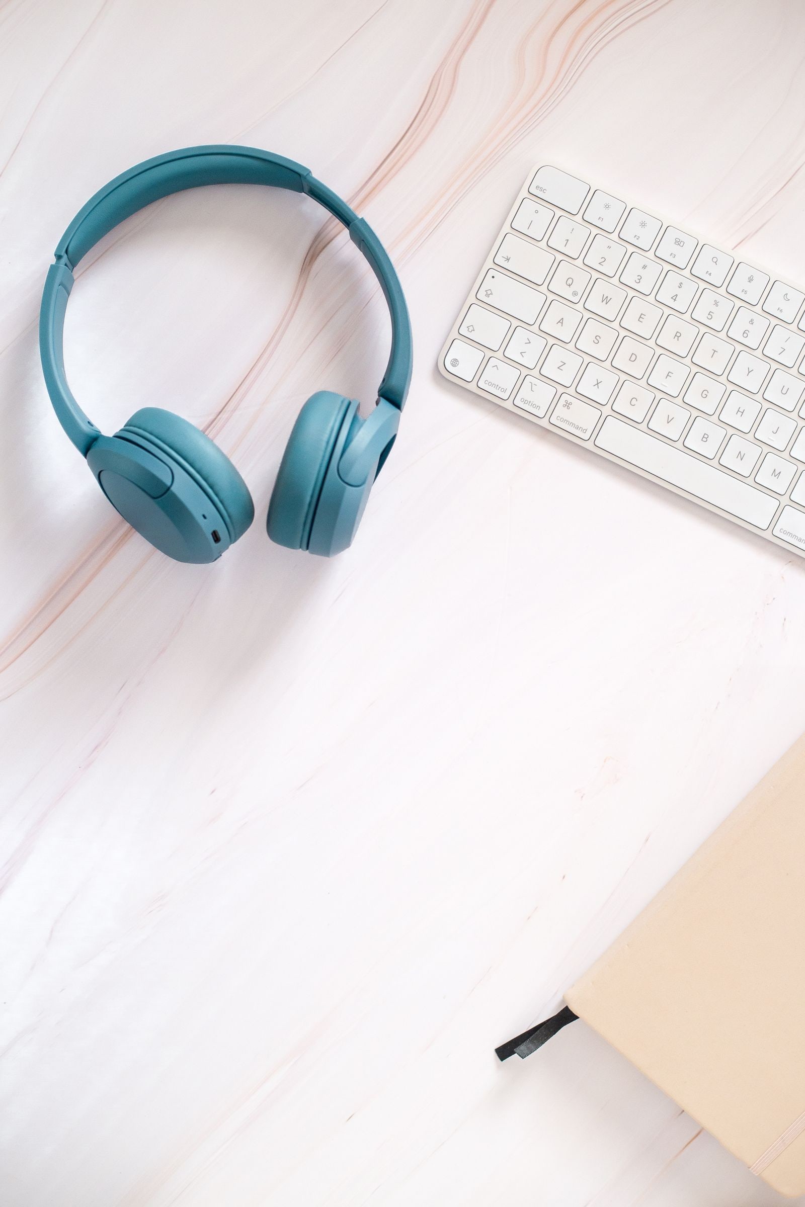 A softly lit desk with a notebook, headphones, and a plant