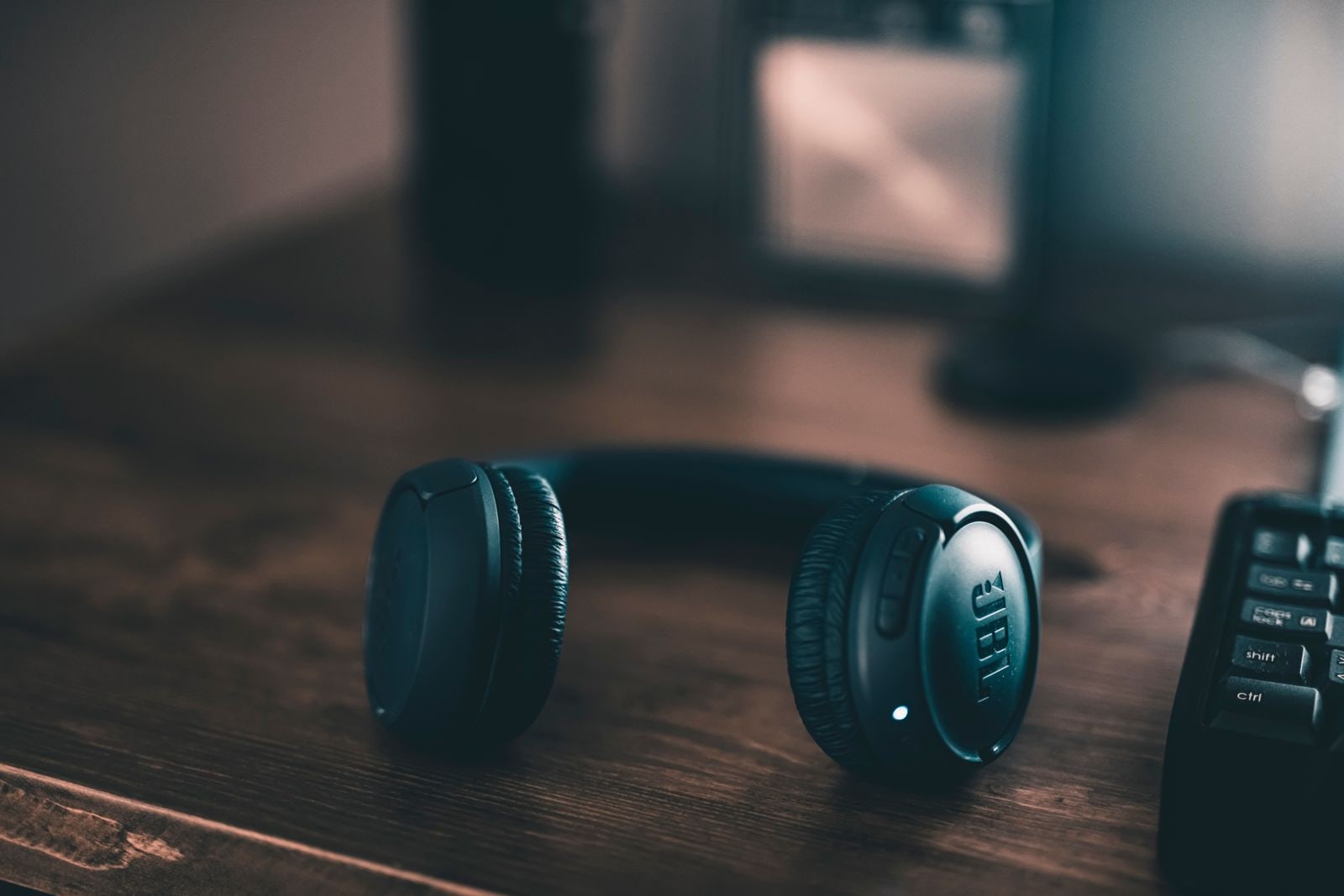 Black headphones resting on a wooden desk