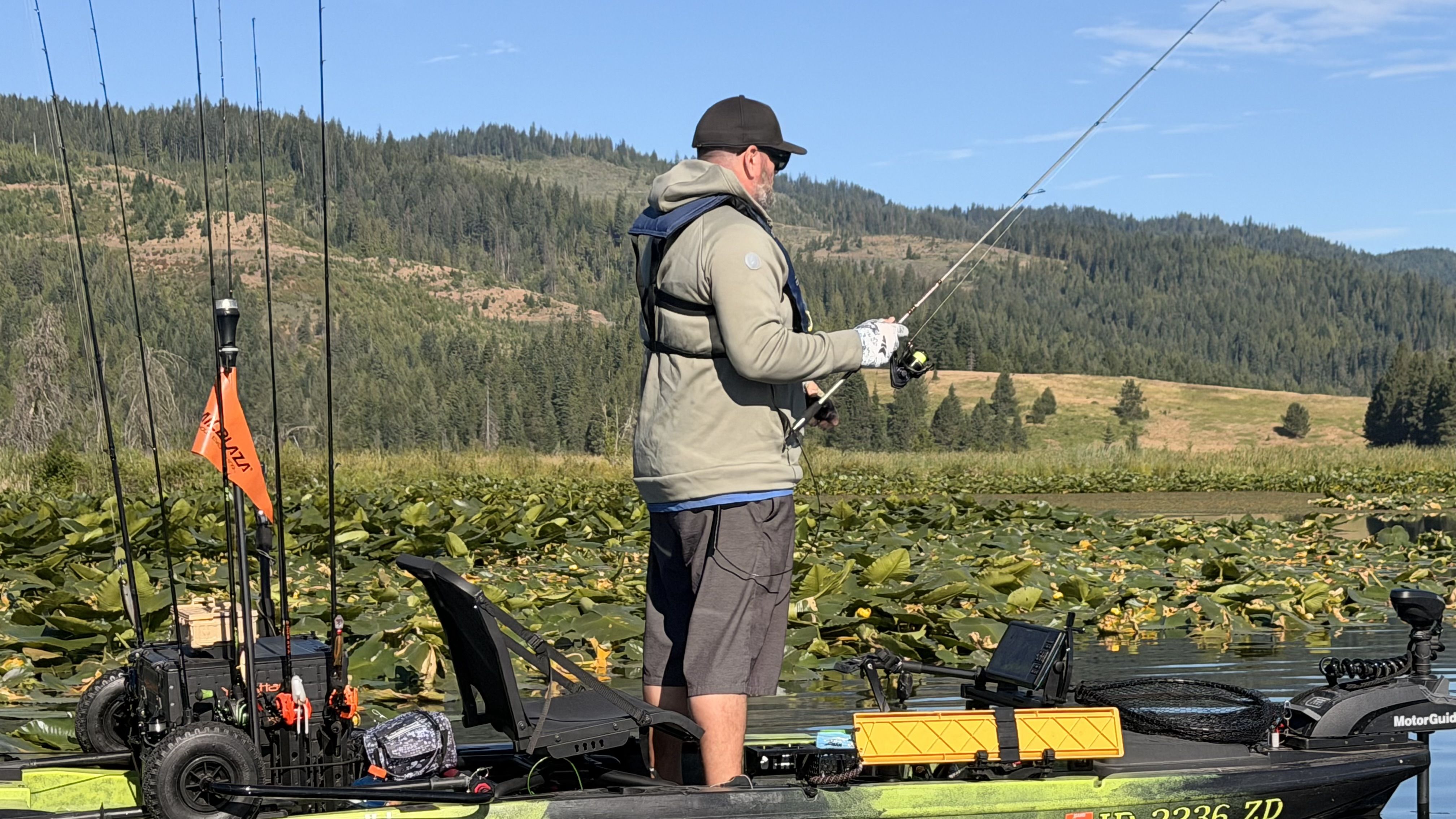 Angler fishing from a kayak among lily pads on a mountain lake