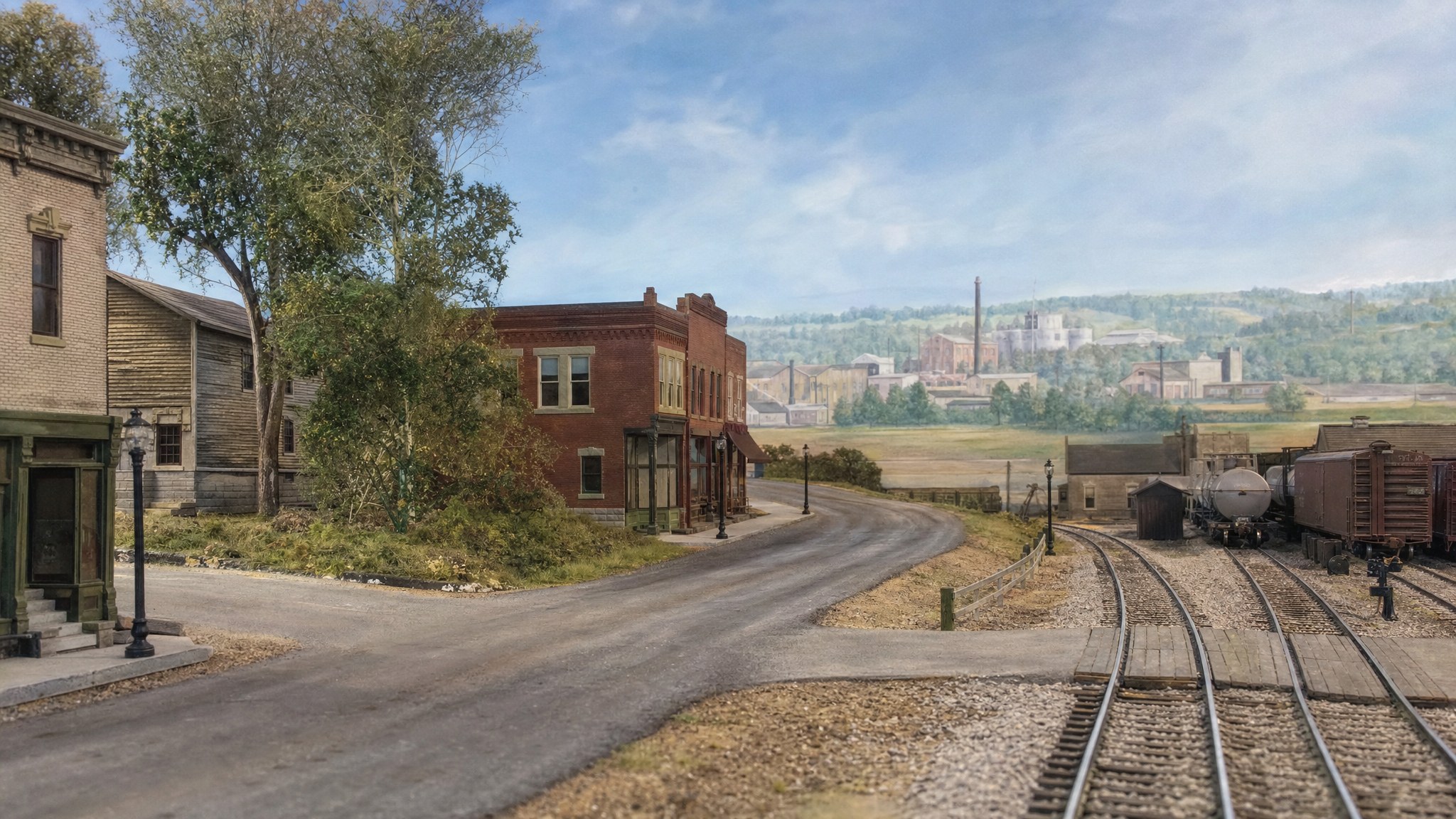 HO scale railroad scene blending from a downtown street into a distant painted backdrop
