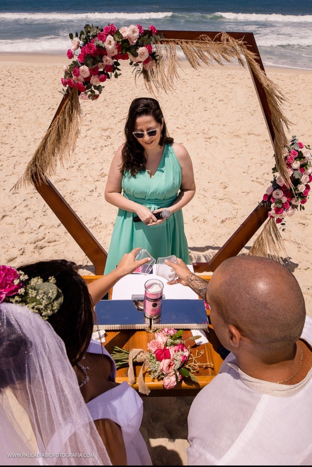 A beach wedding ring exchange framed by flowers and the ocean
