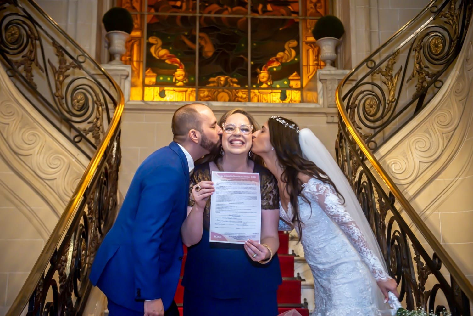 A newly married couple celebrating with their officiant on a staircase