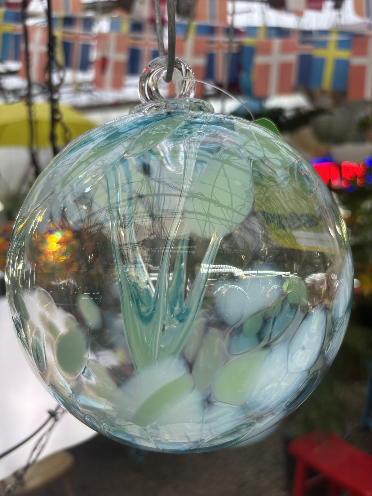 Seafoam green hand-blown glass ball hanging in the greenhouse