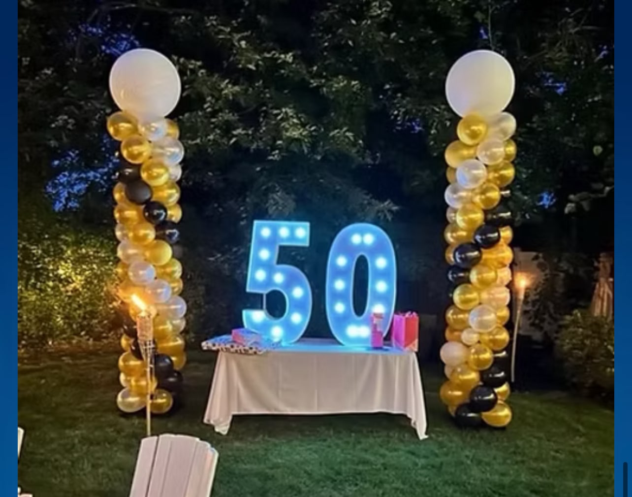Black and gold balloon columns framing a 50th birthday celebration