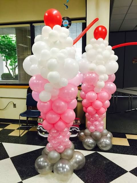 Pink and white ice cream sundae balloon sculptures topped with red balloon cherries