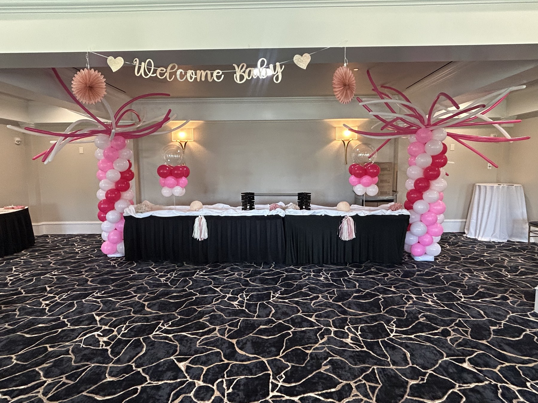 Pink and white balloon columns with bow-shaped details at a baby shower