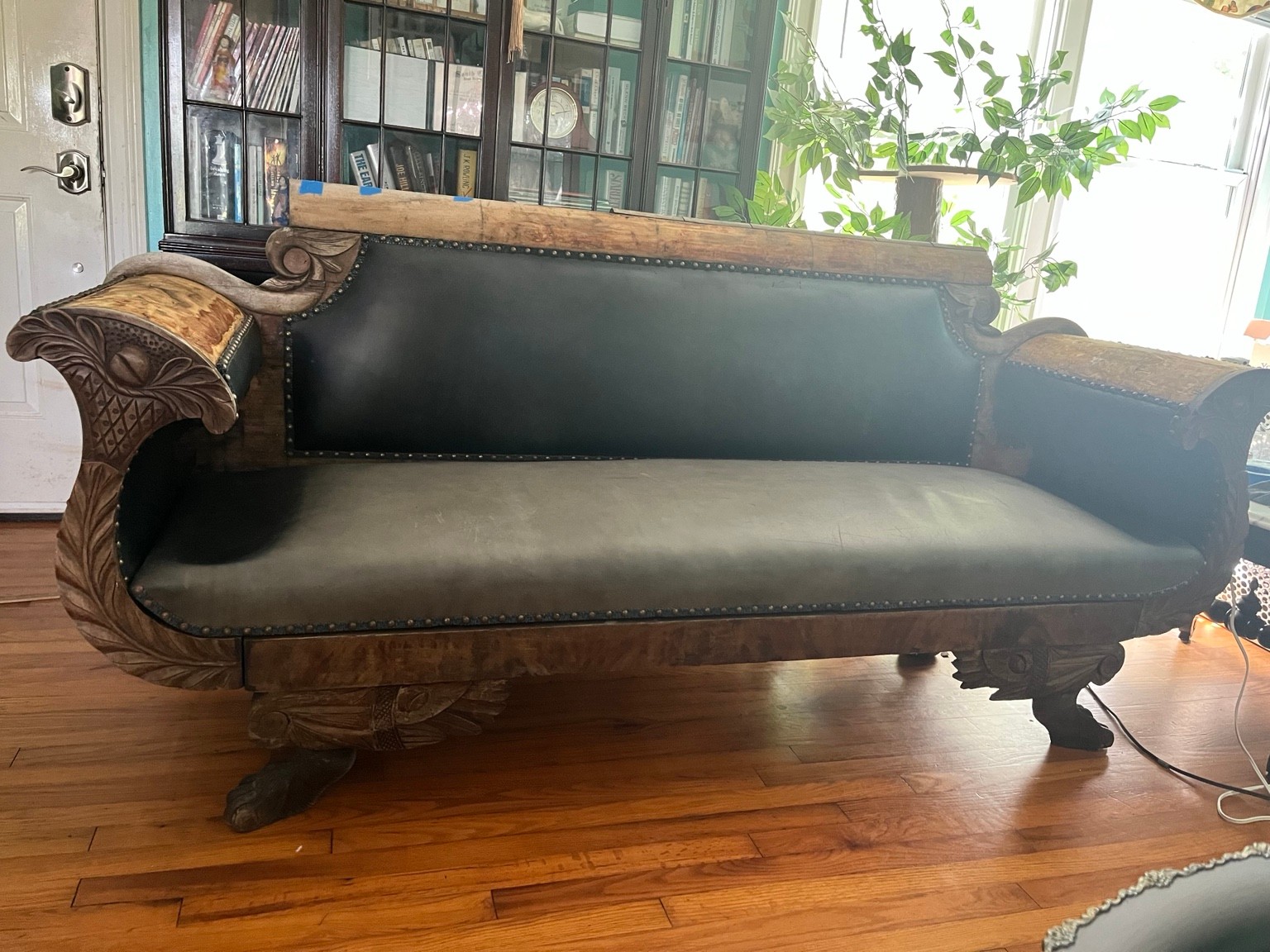 The sofa before its transformation, with dark leather and carved wooden arms.