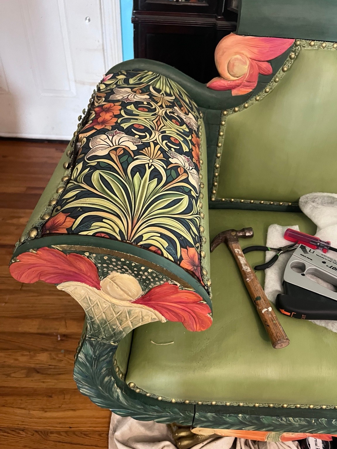 Botanical fabric connects the bolster and arm accents with the painted floral carvings.