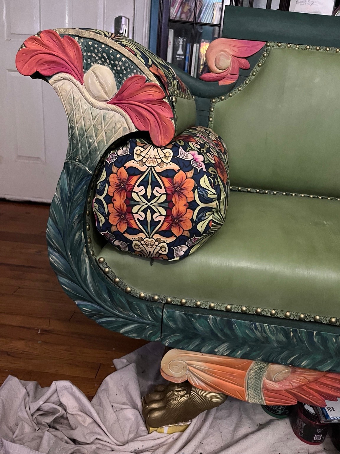 Coral flowers, teal foliage, and gold accents bring the carved arm to life.