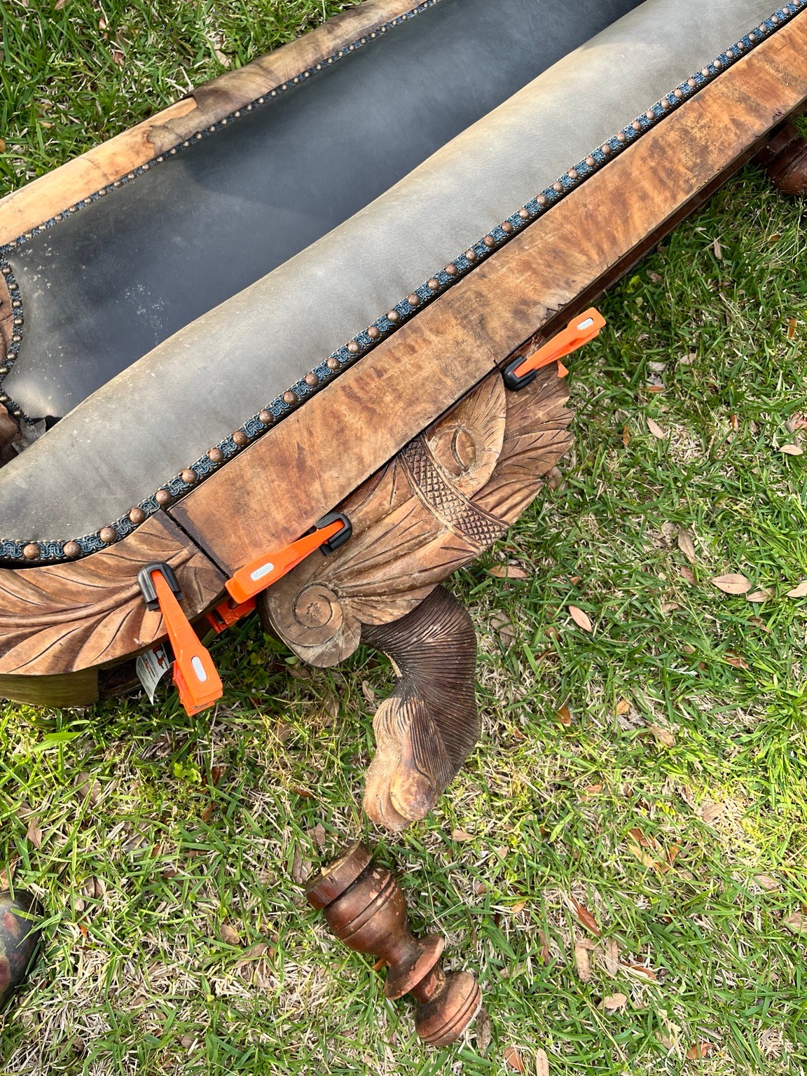 The damaged sofa during repairs, with a detached leg beside it.